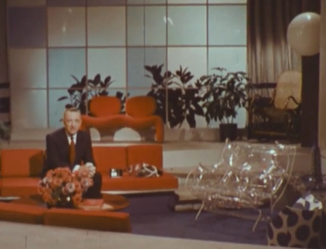 Walter Cronkite, sitting in the very orange living room of the future.
