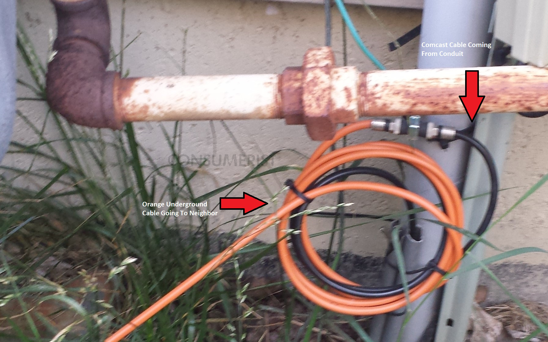 The black cable comes up from the ground and is supposed to go into the house. Instead, it's been pulled out of the conduit and connected to the orange underground-grade cable, which runs down the side yard to a neighboring property (see photo below).