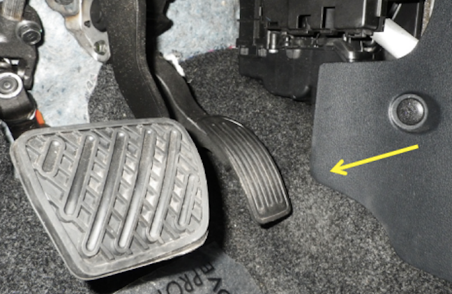 A photo provided by NHTSA shows the area in which drivers' feet have become stuck. The arrow shows the actuator flap that interferes with the movement between the accelerator and brake.