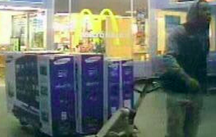 Surveillance video shows a man posing as a Walmart employee stealing four large Samsung TVs.